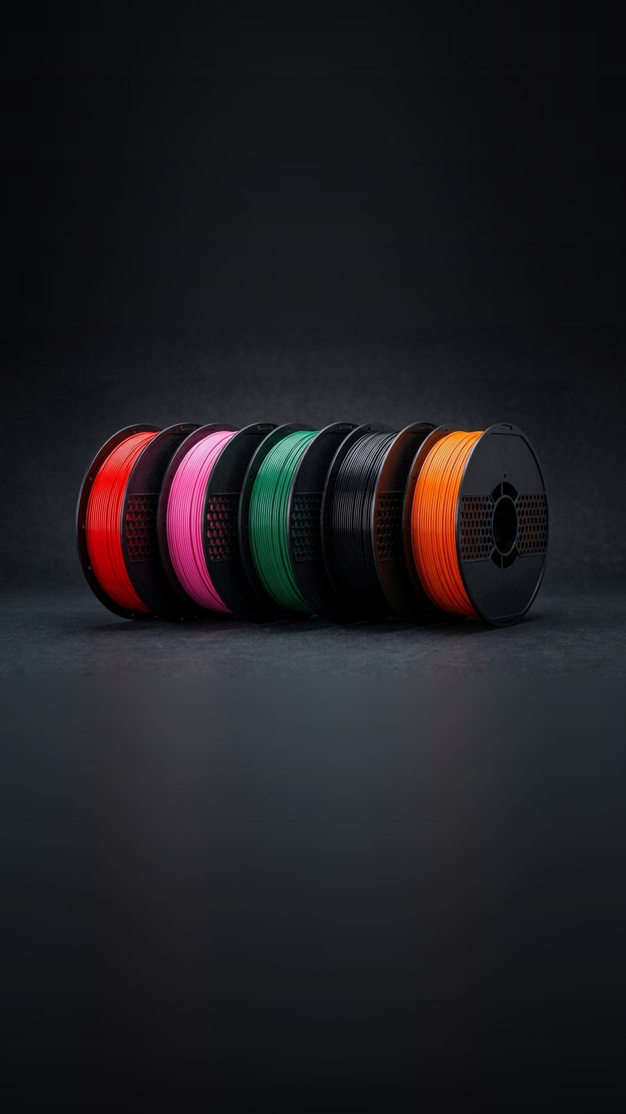 Five DAYOTI filament spools in red, pink, green, black and orange, lined up under studio lighting